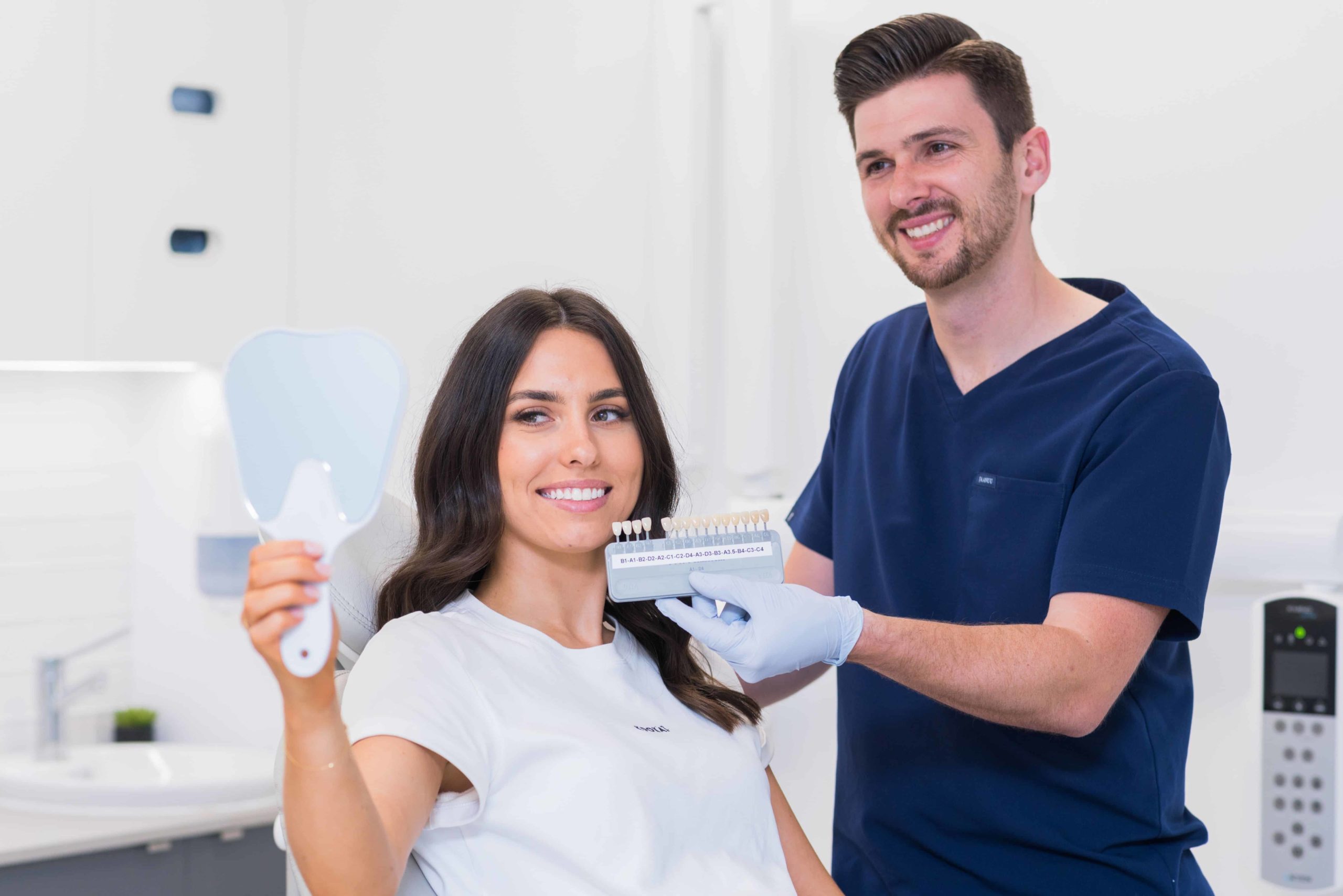 a dentist showing a set of fixtures to a woman holding a mirror