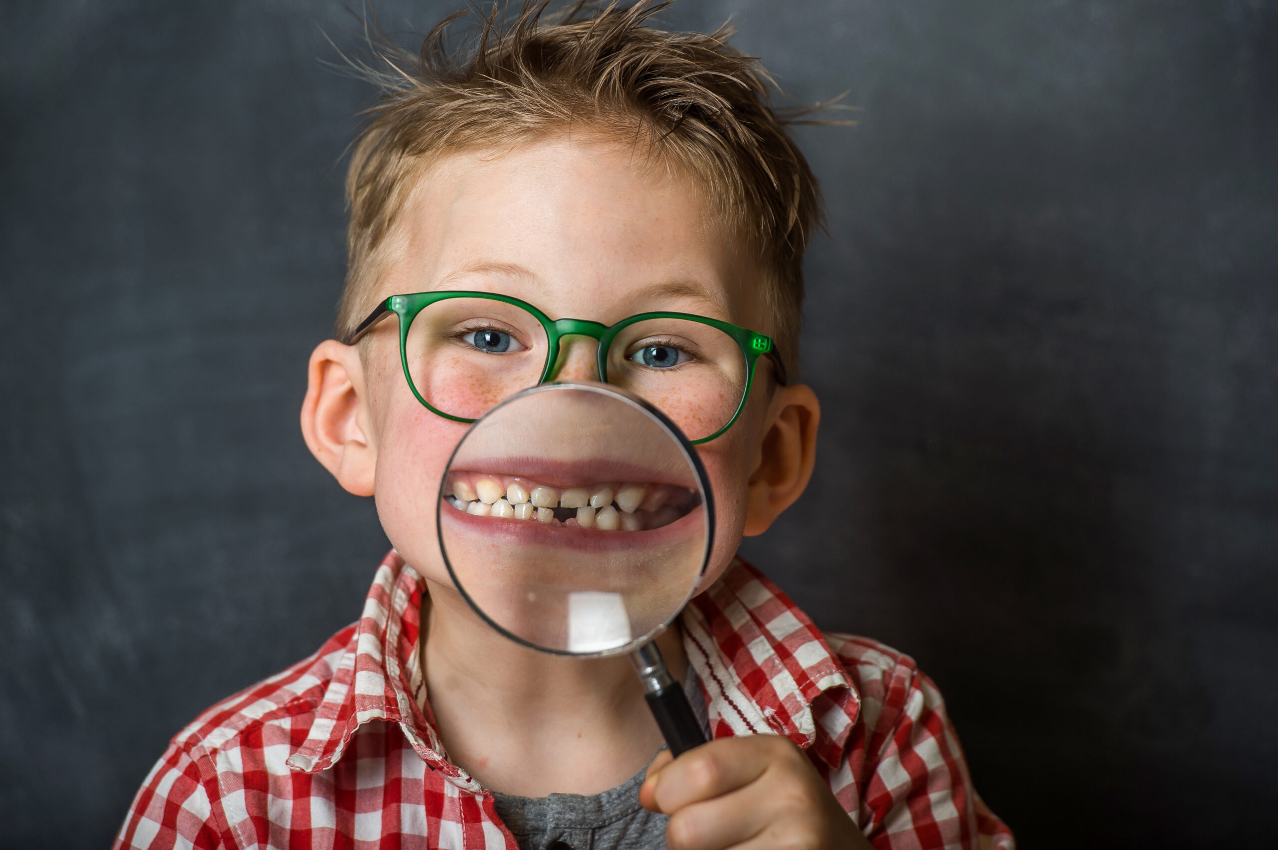 kid showing missing tooth through magnifier